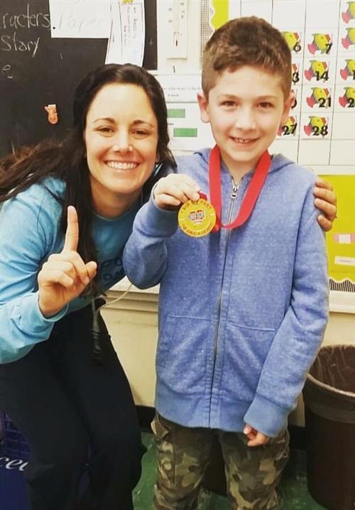 PE Teacher with child holding medal 