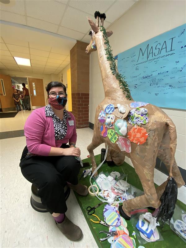 Community artist posing with giraffe sculpture 