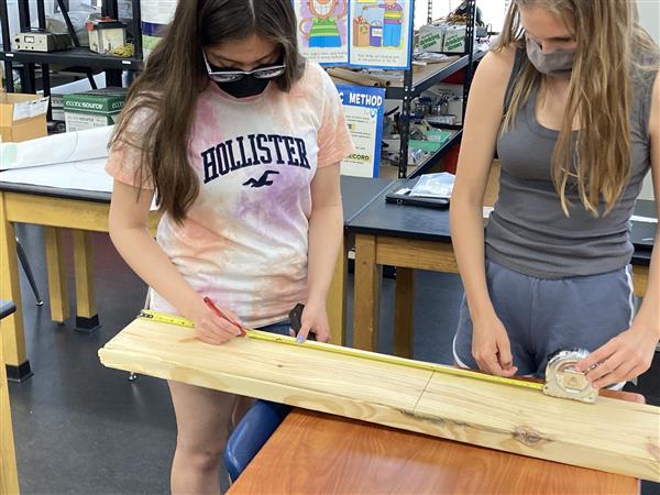 Two students measuring a plank of wood together