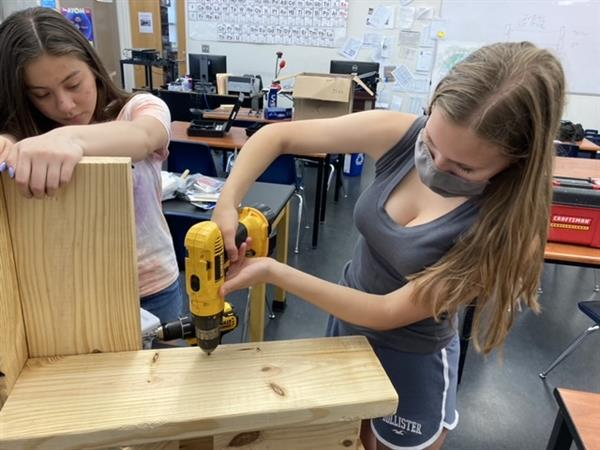 Two students drilling wood together