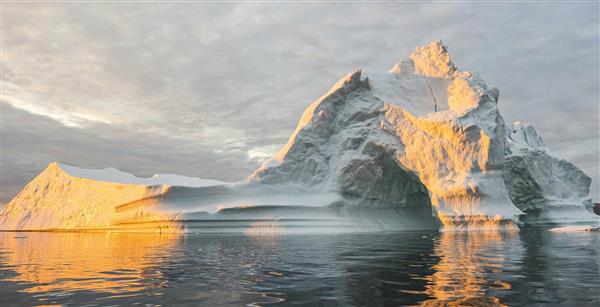 A large ice formation floating in the ocean, with parts melting away.