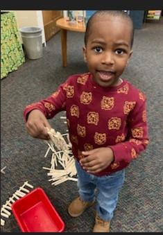 Student building fence with popsicle sticks and clothespins